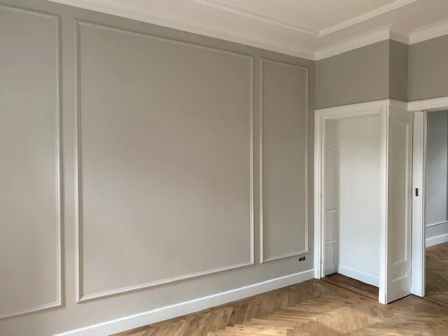 Wand met lijstwerk, witte deur en visgraatparket