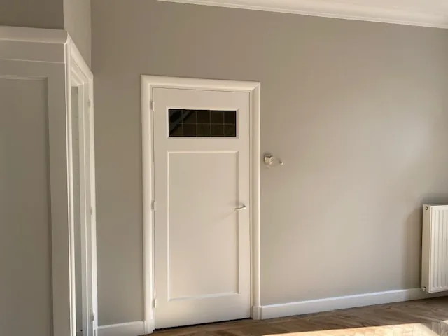 Grijze kamer met witte binnendeur met glasvak