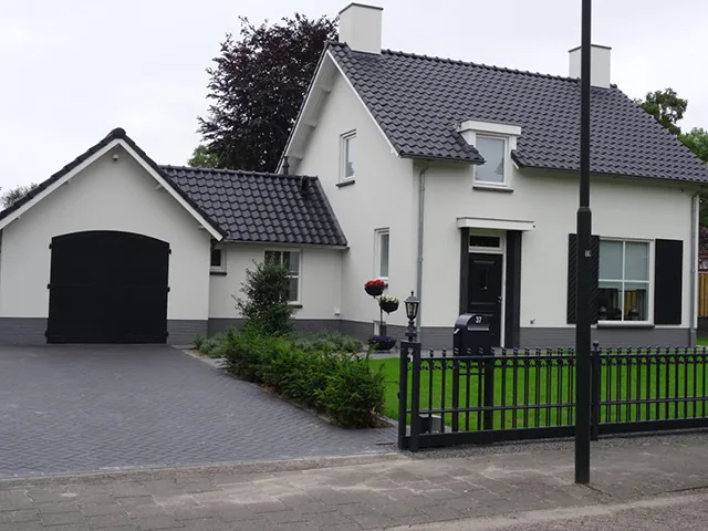 Witte woning met zwarte garagedeur en zwart hek