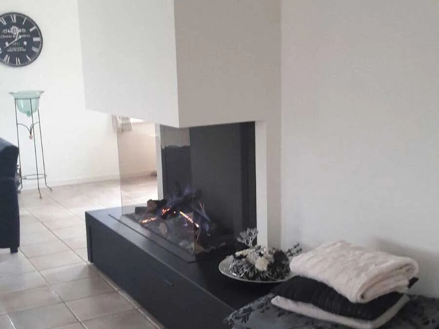 Woonkamer met open haard in een zwart blok en lichte vloer