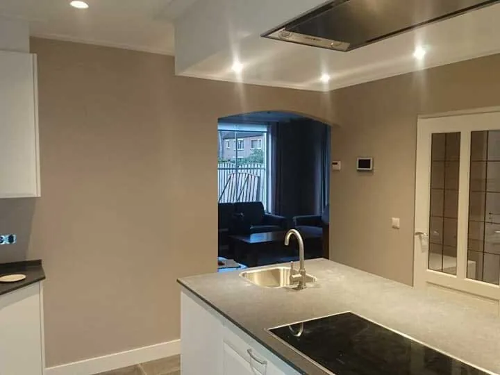 Keuken met taupe wand, witte kastjes en een zwart inductiewerkblad